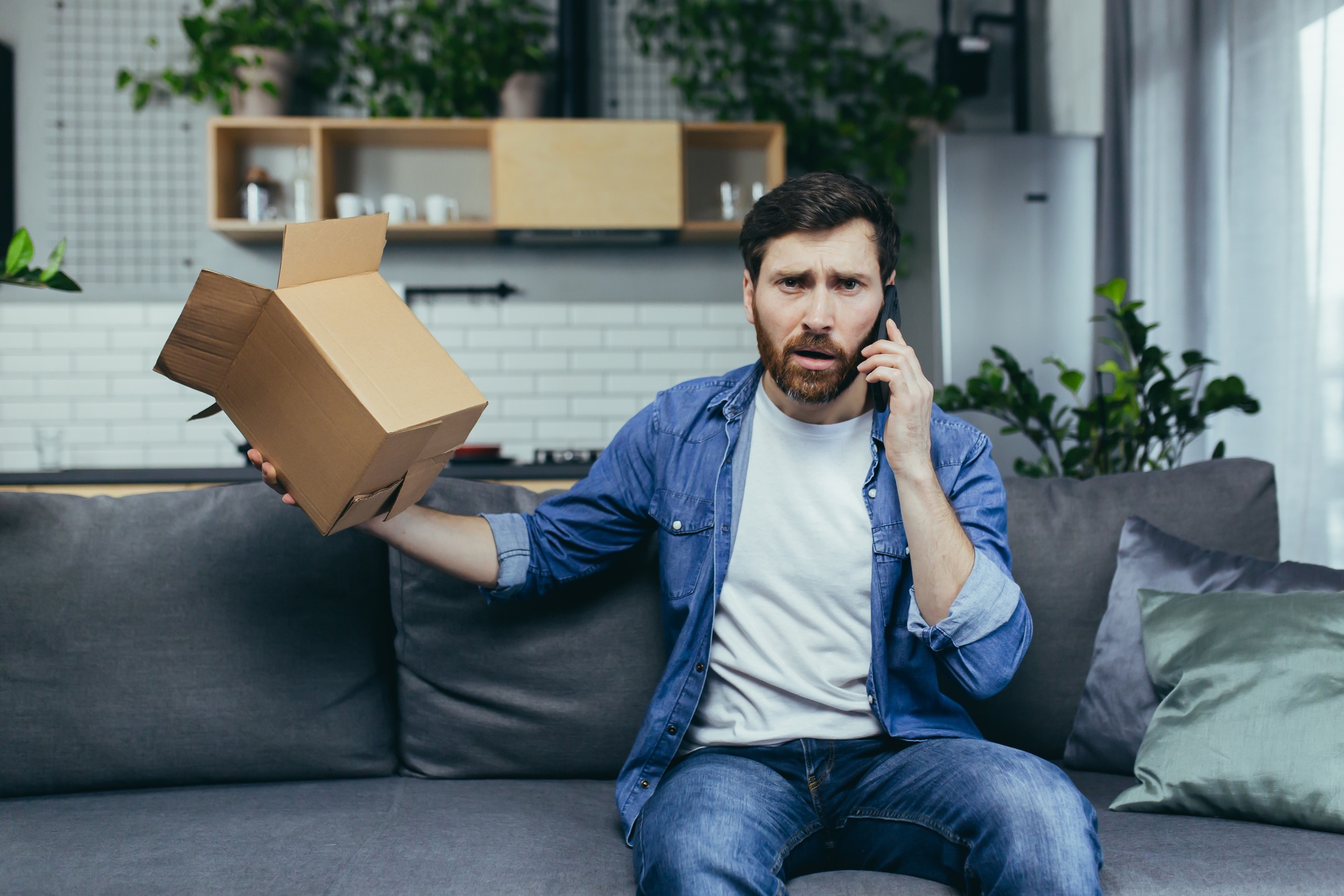 Annoyed and angry man at home received the wrong parcel from the online store